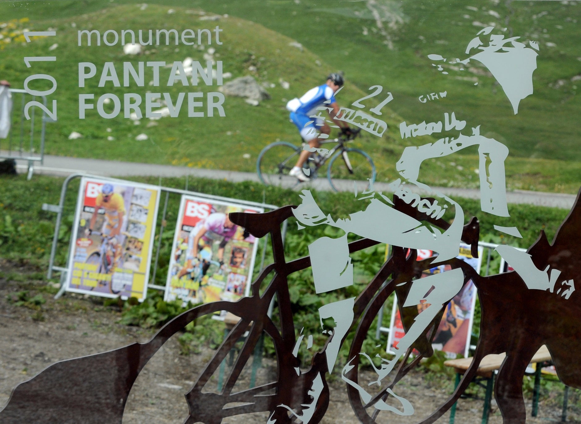 A cyclist is pictured through a glass memorial dedicated to late Italian cyclist Marco Pantani. The memorial was dedicated this week in Valloire, a village on the way to the Galibier. Pantani, the 1998 Tour winner, died from a drugs overdose in a Rimini hotel in 2004. AFP PHOTO / JEAN-PIERRE CLATOT