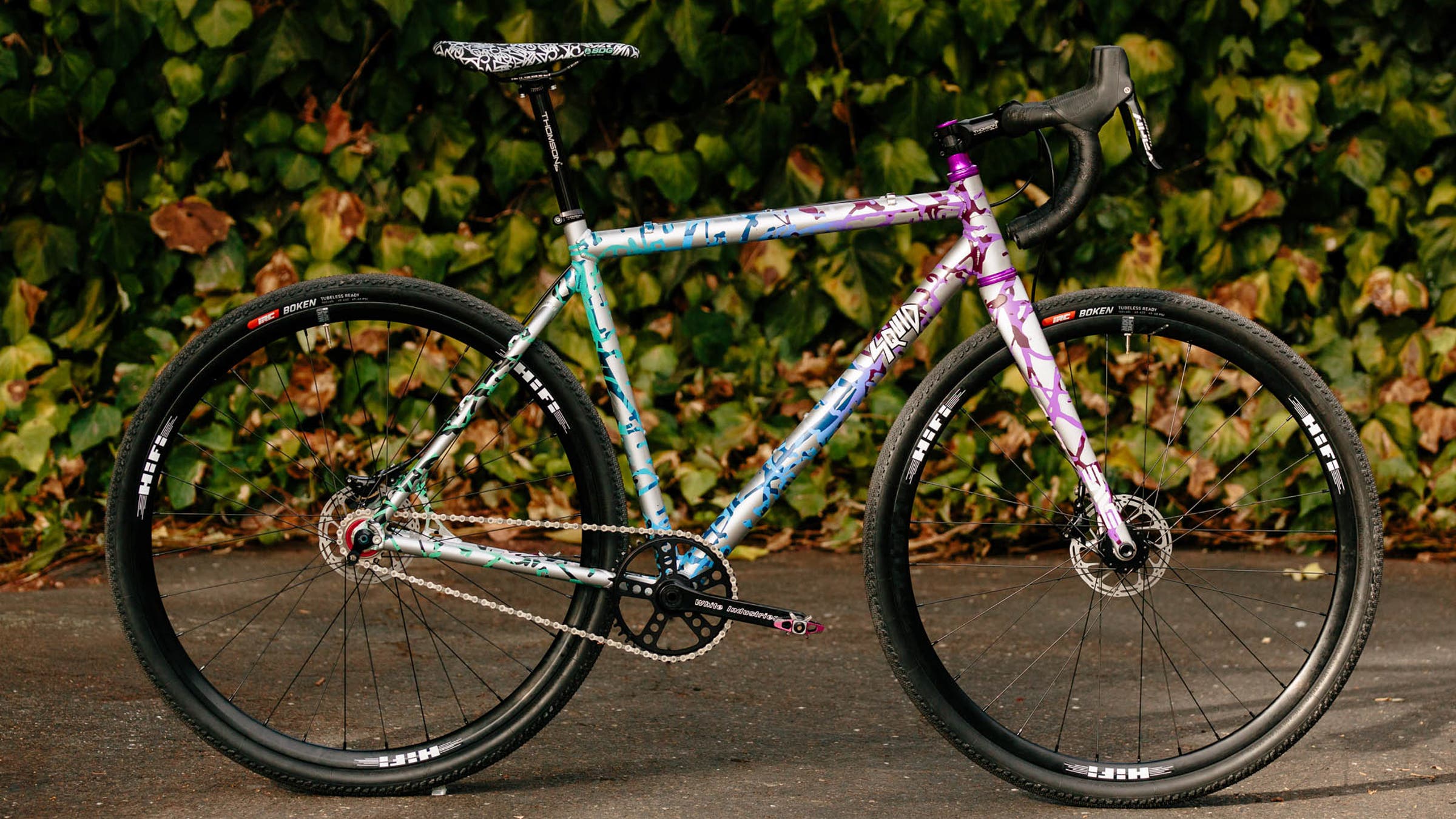 A colorfully painted Squidcross bike in front of some bushes