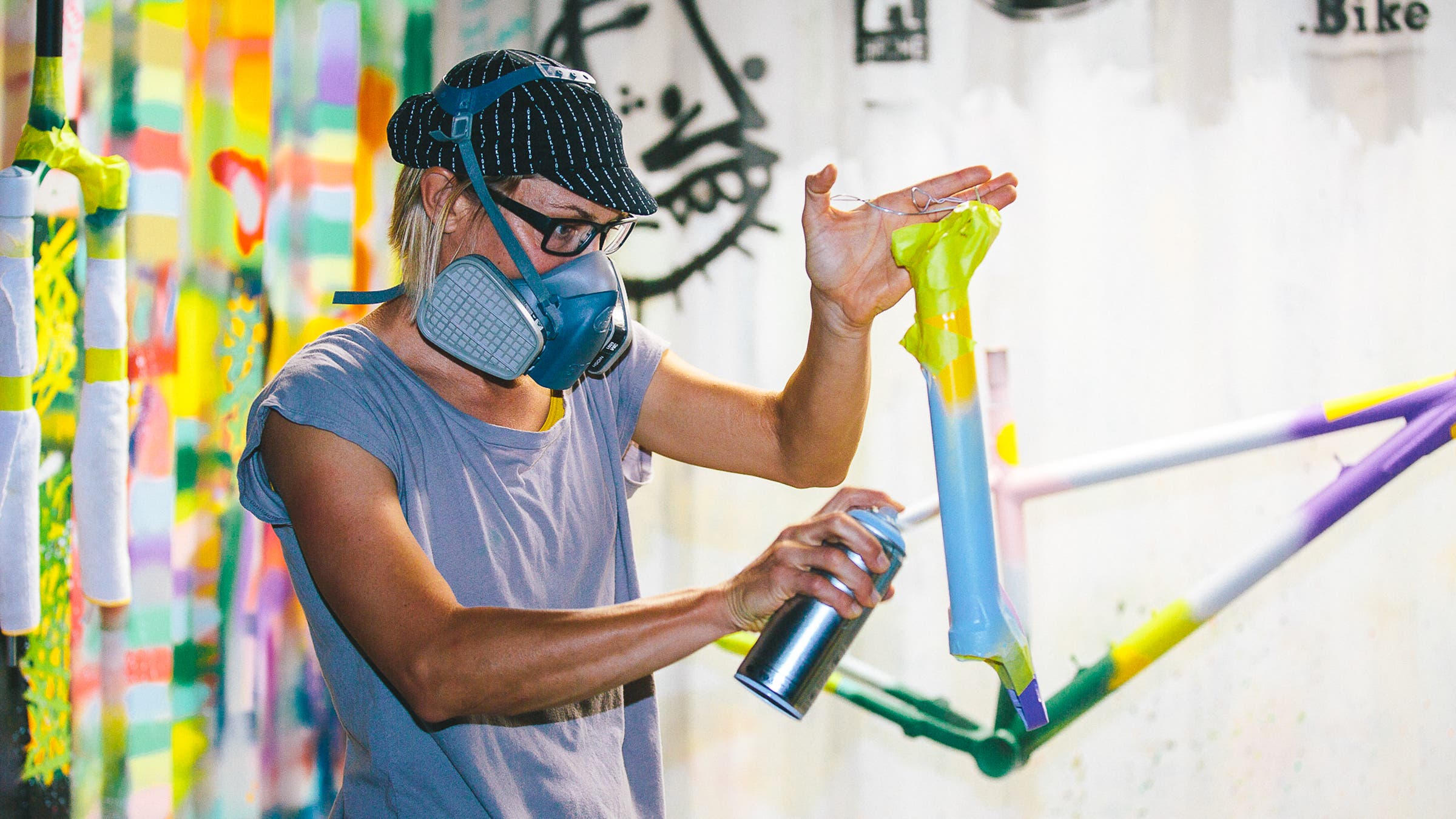 Emily Kachorek spray paints a piece of bike frame