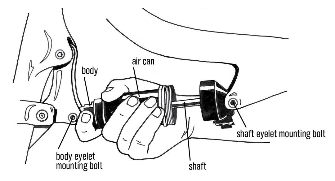 Unscrewing a Fox air can from the shaft eyelet while it’s on the bike