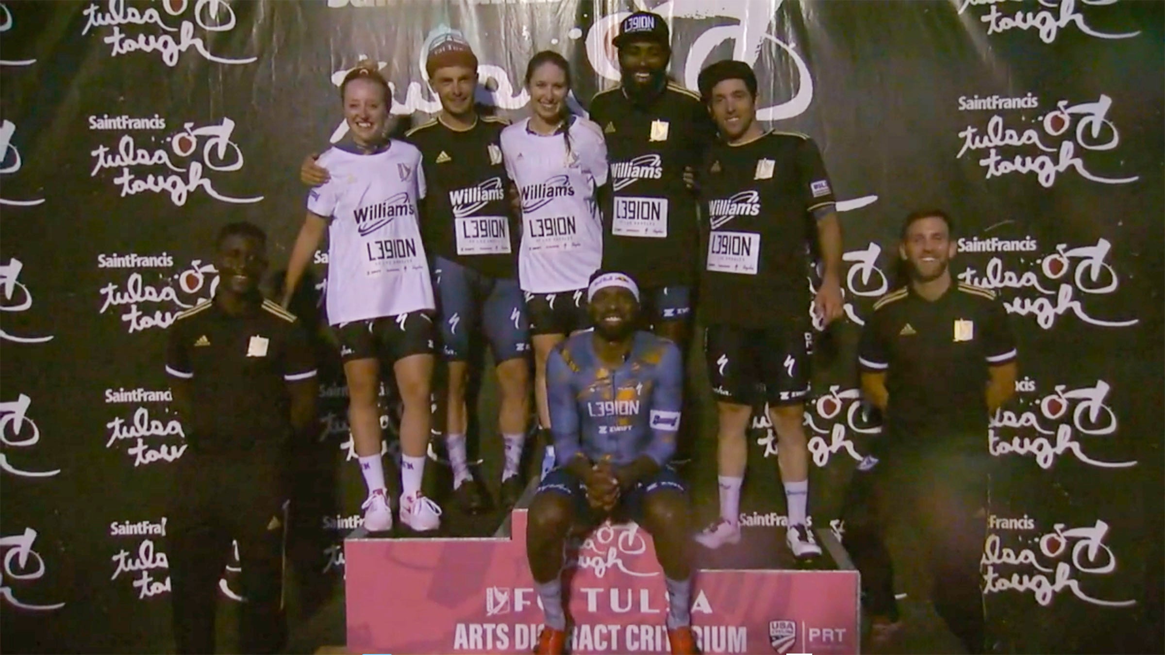 L39ion of Los Angeles dominated Saturday night at Tulsa Tough.  FC Tulsa sponsored the event, and the L39ion team took to the podium together. In white FC Tulsa jerseys are women's winner Kendall Ryan (center) and Skyler Schneider. In black FC Tulsa jerseys are winner Cory Williams (black hat), Tyler Williams and Ty Magner. Team founder Justin Williams is seated, and representatives of FC Tulsa flank the podium.