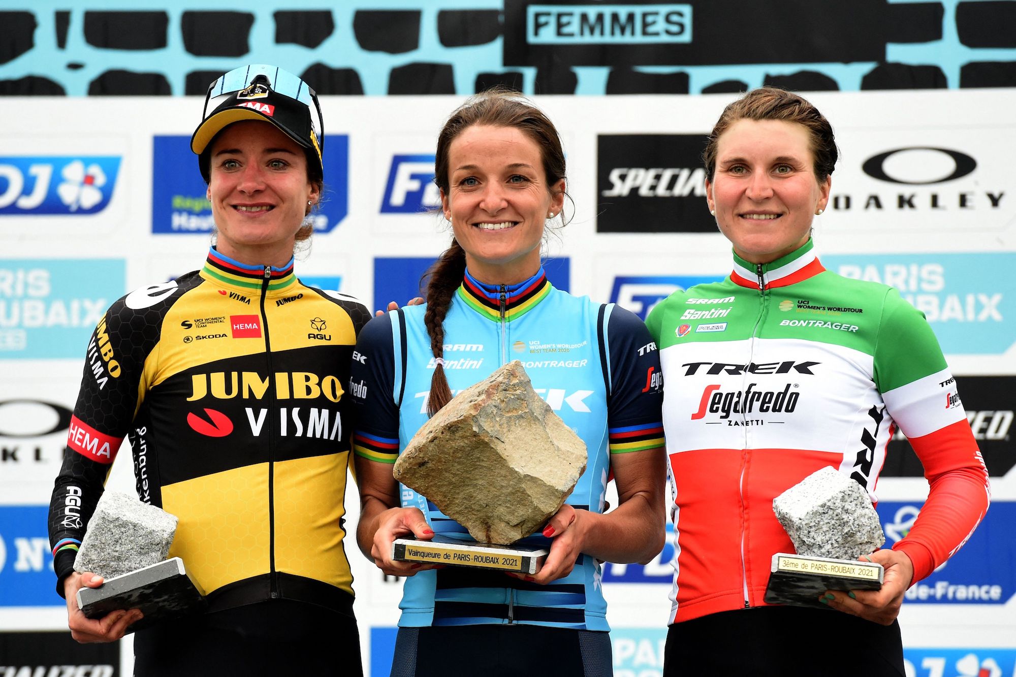 UK's Elizabeth Lizzie Deignan holds the trophy after she won the first edition of the women elite race of the 'Paris-Roubaix' cycling event, with second-placed Dutch cyclist Marianne Vos (L) and third-placed Italian cyclist Elisa Longo Borghini (R), in Roubaix, on October 2, 2021. (Photo by FRANCOIS LO PRESTI / AFP) (Photo by FRANCOIS LO PRESTI/AFP via Getty Images)