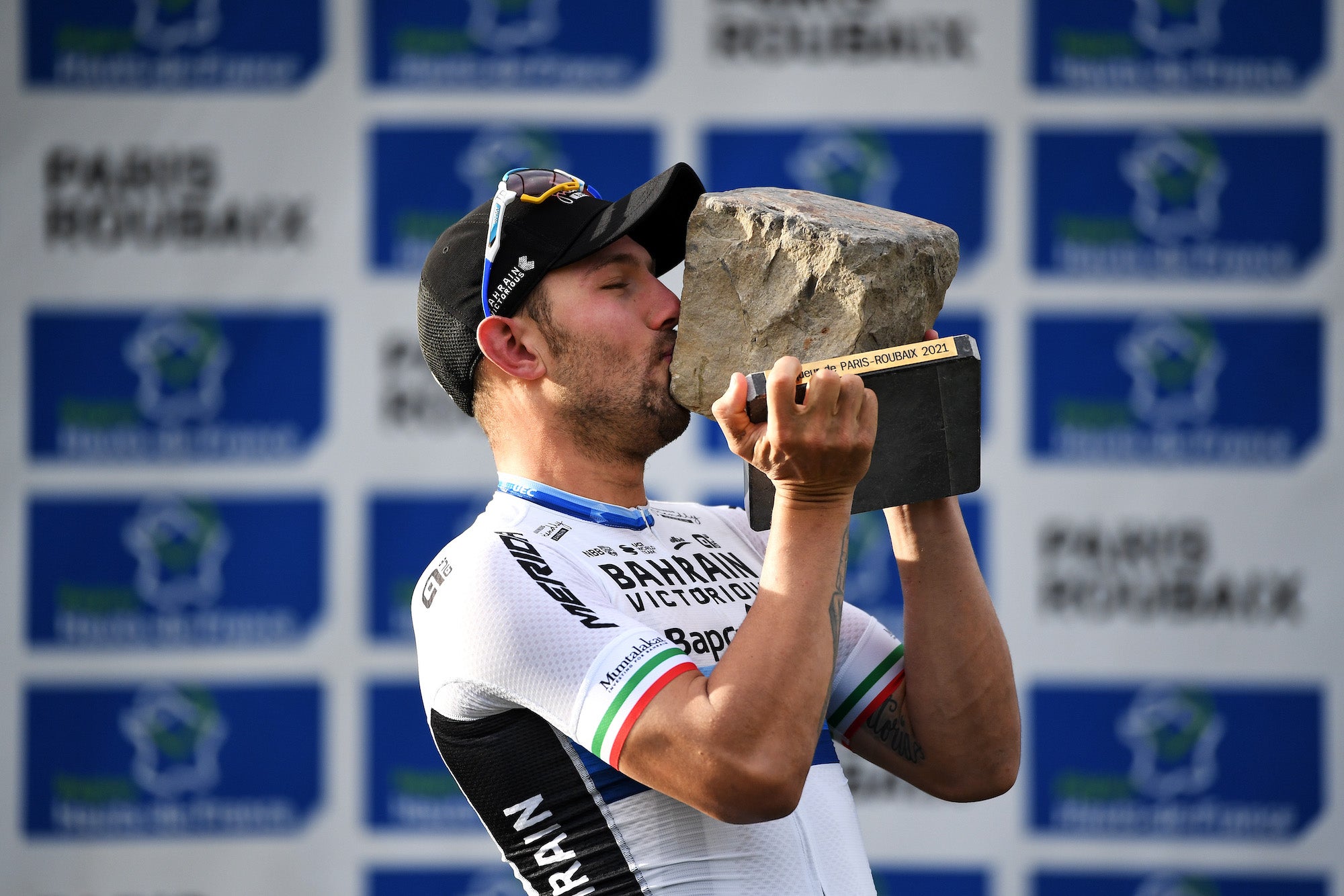 ROUBAIX, FRANCE - OCTOBER 03: Sonny Colbrelli of Italy and Team Bahrain Victorious celebrates winning the race and kisses his cobblestone trophy on the podium ceremony after the 118th Paris-Roubaix 2021 - Men's Eilte a 257,7km race from Compiègne to Roubaix / #ParisRoubaix / on October 03, 2021 in Roubaix, France. (Photo by Tim de Waele/Getty Images)