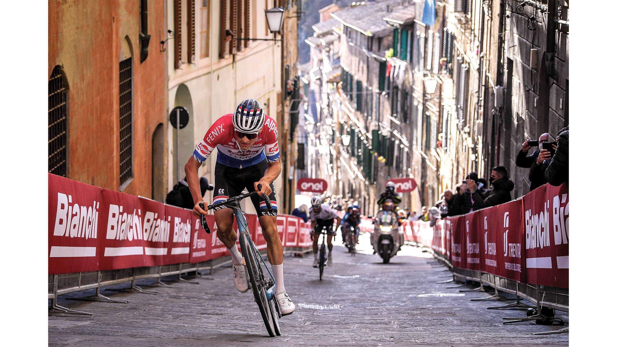 Van der Poel climbing up a steep, narrow incline between buildings