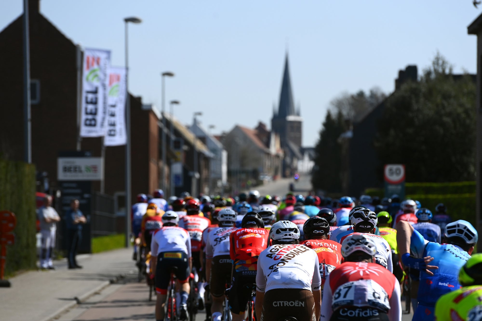 HARELBEKE, BELGIUM - MARCH 25: A general view of the peloton passing through Wortegem-Petegem Village with a church in the background during the 65th E3 Saxo Bank Classic 2022 a 203,9km one day race from Harelbeke to Harelbeke / #E3SaxobankClassic / #WorldTour / on March 25, 2022 in Harelbeke, Belgium. (Photo by Tim de Waele/Getty Images)
