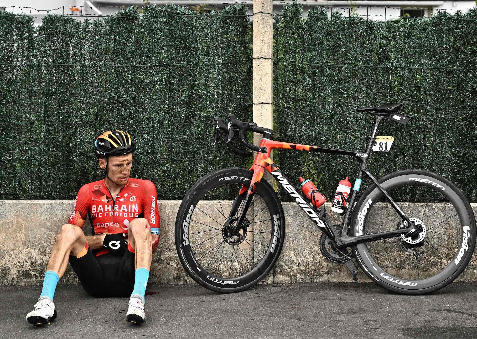 Jack Haig rests against a wall after crashing hard in Wednesday's stage.