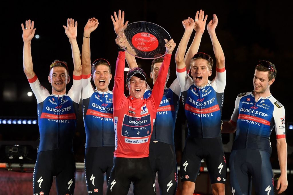 Team Quick Step's Belgian rider Remco Evenepoel (C) celebrates with teammates on the podium wearing the overall leader's red jersey after the 21st and last stage of the 2022 La Vuelta cycling tour of Spain, a 96.7km race from Las Rozas de Madrid to Madrid, on September 11, 2022. - Belgian rider Remco Evenepoel claimed his first Grand Tour victory in the Vuelta a Espana in Madrid. The 22-year-old dominated the three-week race, taking victory after the 21st and final stage won by Colombian Juan Sebastian Molano. (Photo by OSCAR DEL POZO / AFP) (Photo by OSCAR DEL POZO/AFP via Getty Images)